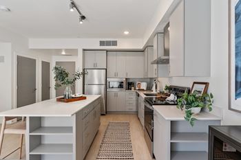 A modern kitchen with a white countertop and stainless steel appliances.